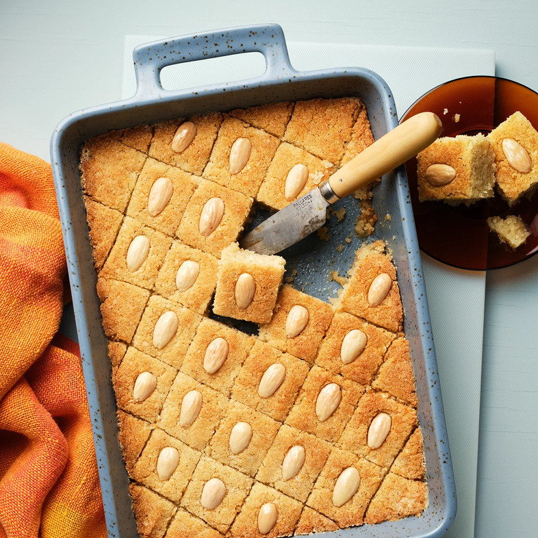 Gyllenbrun mannagrynskaka skuren i rutor med en mandel i varje bit, glansig av sockerlag.