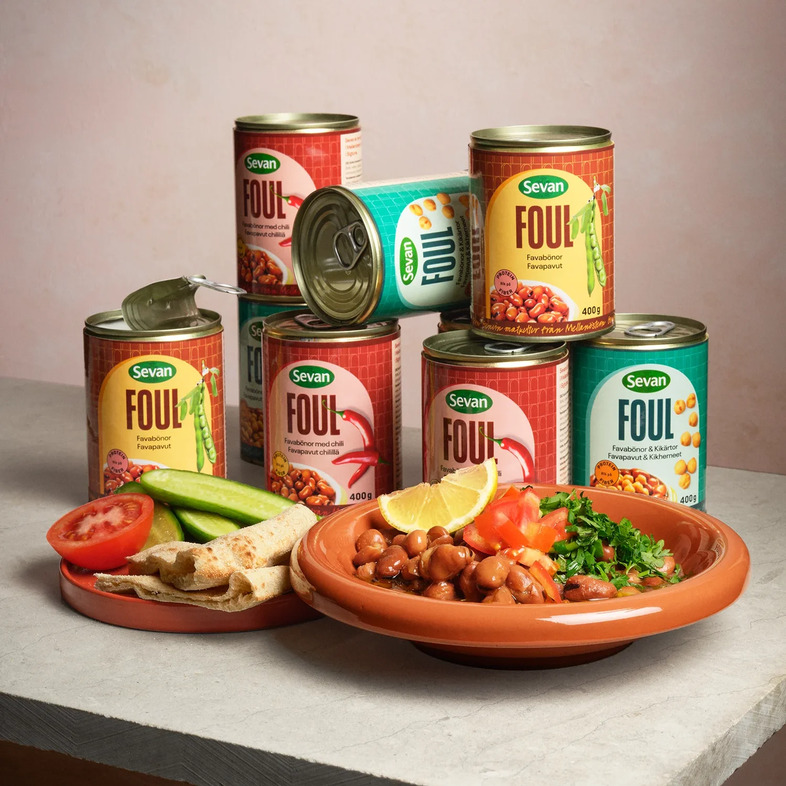 Tallrik med varma bondbönor toppade med hackade tomater, persilja och mynta, ringlad olivolja och citronklyftor vid sidan.