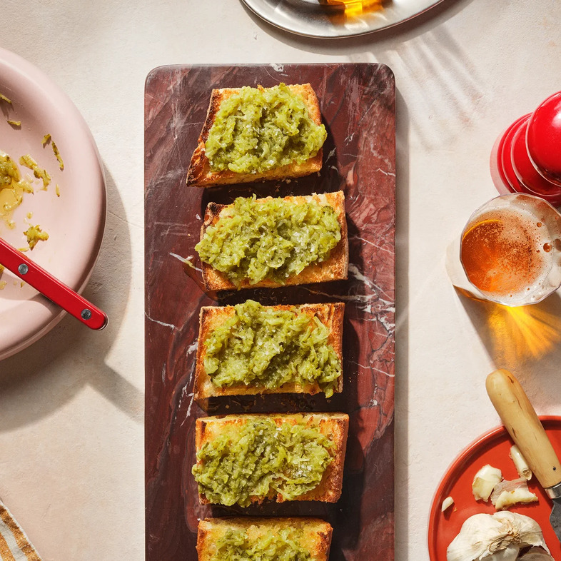 Krispigt vitlöksbröd toppat med rivna turkiska cornichons och olivolja, serverat som tilltugg.
