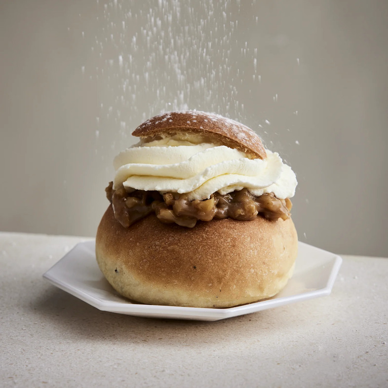 Halva semla fylld med krämig valnöts- och halvamassa toppad med vispad grädde och pudrad med florsocker.